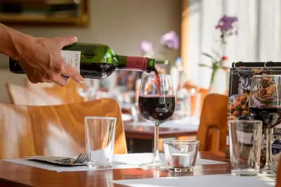 a person pouring wine into a glass on a table at Campanile Hotel & Restaurant Brussels Vilvoorde in Vilvoorde