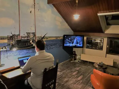 a man sitting at a desk in a room with a laptop at B&B Bij MoeMee in Ghent