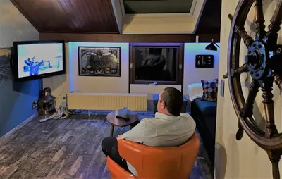 a man sitting in an orange chair watching tv at B&B Bij MoeMee in Ghent