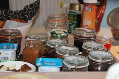 a table with jars of honey and a plate of food at B&B Eat&Sleep in Evergem