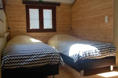 two beds in a room with wooden walls at Vakantiestudio 'Kleine Johannes' in Duffel