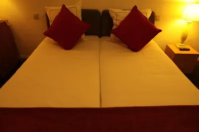 a bedroom with a bed with two red pillows at Hotel De Spiegel in Sint-Niklaas