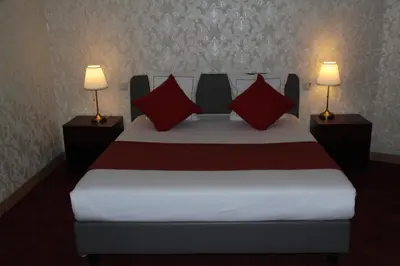 a bedroom with a bed with red pillows and two lamps at Hotel De Spiegel in Sint-Niklaas