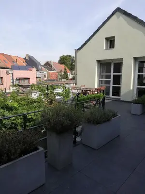 a patio with a table and some plants and a building at Touristflat Dewulf in Ghent