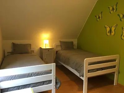 two beds in a room with green walls at Stropershuisje in Stekene