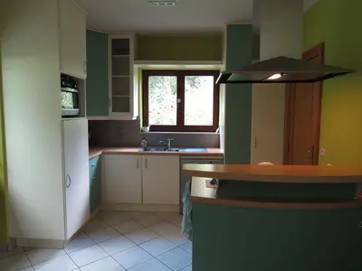 a kitchen with green and white cabinets and a window at Stropershuisje in Stekene