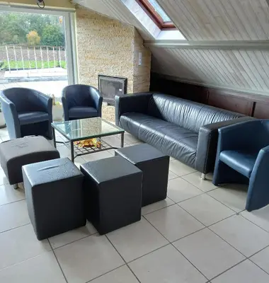 a living room with a leather couch and chairs at B&B Aalsters-genot in Aalst
