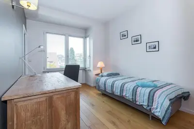 a bedroom with a bed and a desk and a window at Fantastic Large House in Brussels