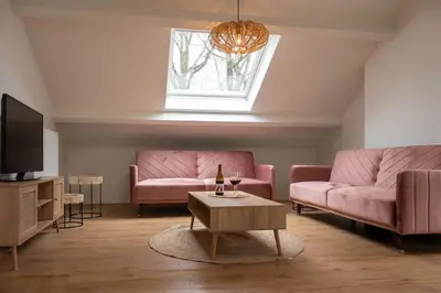 a living room with pink couches and a tv at Huize Nassau in Zelem