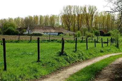 a fence on a field with a house in the background at Huize Nassau in Zelem