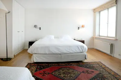 a white bedroom with two beds and a rug at Ter Heide (Kaprijke - Lembeke) in Lembeke