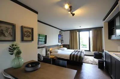 a bedroom with a bed and a table and a dining room at Getaway Brussels Airport in Zaventem