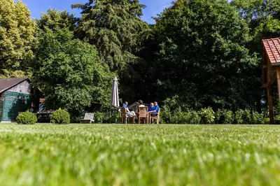 a group of people sitting in chairs in a yard at B&B 't Heirweggoed in Assenede