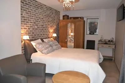 a bedroom with a bed and a brick wall at B&B 't Heirweggoed in Assenede