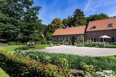people sitting on a bench in front of a building at B&B 't Heirweggoed in Assenede