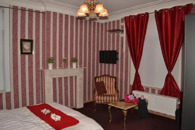 a bedroom with a bed and a chair and red curtains at Hotel Het Gasthof in Herent