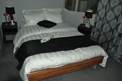 a bed with a black and white comforter and flowers on it at Hotel Het Gasthof in Herent