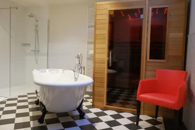 a bathroom with a tub and a red chair at B&B Domein Rodin in Oud-Turnhout
