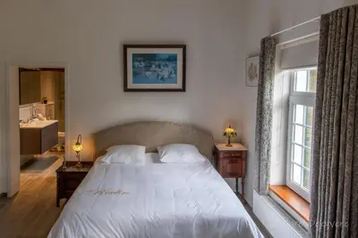 a bedroom with a white bed and a bathroom at B&B Domein Rodin in Oud-Turnhout