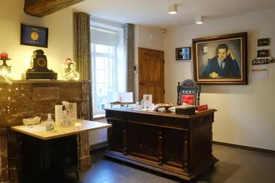 a room with a table and a portrait of a man at B&B Domein Rodin in Oud-Turnhout