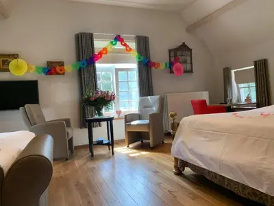 a bedroom with a bed and a room with chairs at B&B Domein Rodin in Oud-Turnhout
