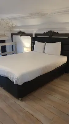 a large bed with a black frame and white pillows at Guesthouse Marie Therese in Brussels