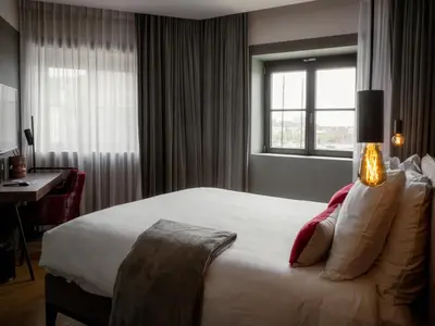 a hotel room with a bed and a desk and a window at U Eat & Sleep Antwerp in Antwerp