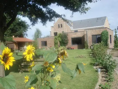 a house with a yard with yellow sunflowers at B&B Mussenzele in Haaltert