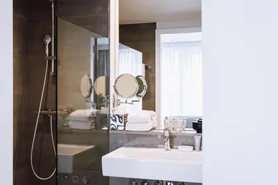 a bathroom with a sink and a shower with a mirror at Pillows City Hotel Brussels Centre in Brussels