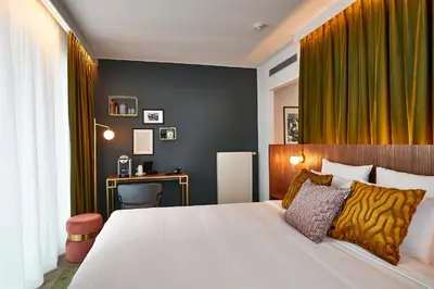 a bedroom with a large white bed and a desk at The Scott Hotel Brussels in Brussels