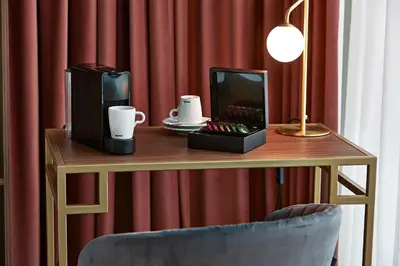 a wooden table with a desk with a chair and a table with a lamp at The Scott Hotel Brussels in Brussels