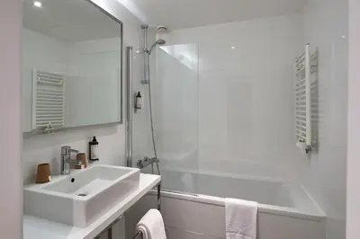 a white bathroom with a sink and a shower at The Scott Hotel Brussels in Brussels