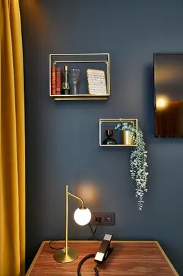 a room with a desk with a lamp and a blue wall at The Scott Hotel Brussels in Brussels