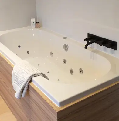 a bath tub with a faucet in a bathroom at Hotel B - Boskapelhoeve in Buggenhout