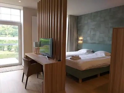 a bedroom with a bed and a desk with a television at Hotel B - Boskapelhoeve in Buggenhout