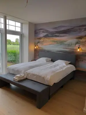 a bedroom with a large bed with a painting on the wall at Hotel B - Boskapelhoeve in Buggenhout