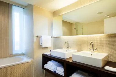 a bathroom with two sinks and a tub and a mirror at Park Inn by Radisson Antwerp City Centre in Antwerp