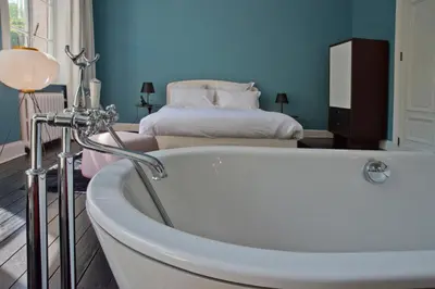 a bath tub in a room with a bed at Appartement Chic in Brussels
