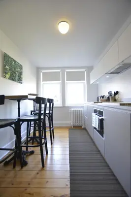 a kitchen with white cabinets and a table and chairs at Appartement Chic in Brussels