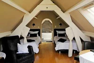 a attic room with two beds and a chair at B&B Bertem Natuur in Leuven