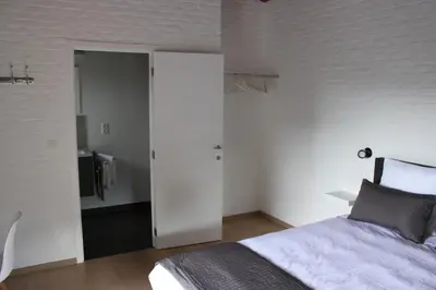 a bedroom with a bed and a white wall at B&B 't Hoogste in Bornem