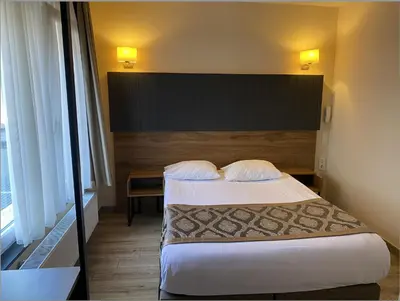 a hotel room with a bed with two pillows at Hotel Prestige in Brussels