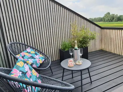 a table and chairs on a balcony with a bottle of wine at B&B De Stuifduinen in Wetteren