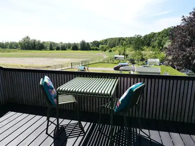 a deck with two chairs and a table and a view of a field at B&B De Stuifduinen in Wetteren
