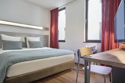 a bedroom with a bed and a desk and window at Hôtel Aqua by HappyCulture in Brussels