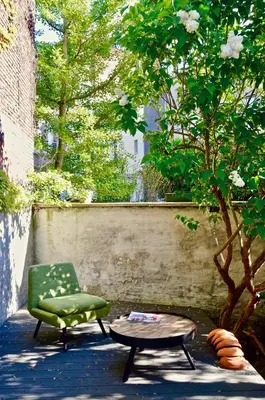 a green chair and a table next to a tree at Rock Lobster City Lodge in Antwerp