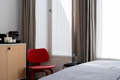 a bedroom with a red chair next to a bed at Hotel Julien in Antwerp