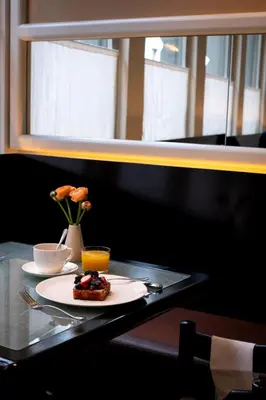 a table with a plate of food and a vase with flowers at Hotel Julien in Antwerp