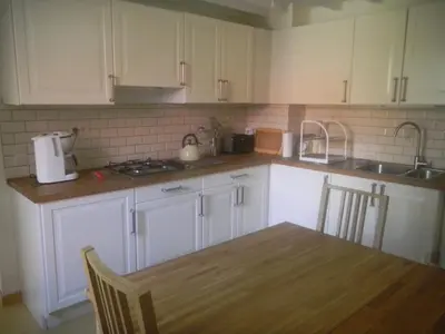 a kitchen with white cabinets and a wooden table at Verreveld in Londerzeel