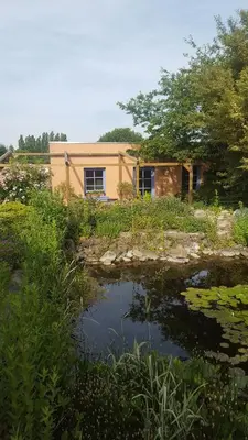 a house with a pond in front of it at B&B La Clé du Sud in Merelbeke